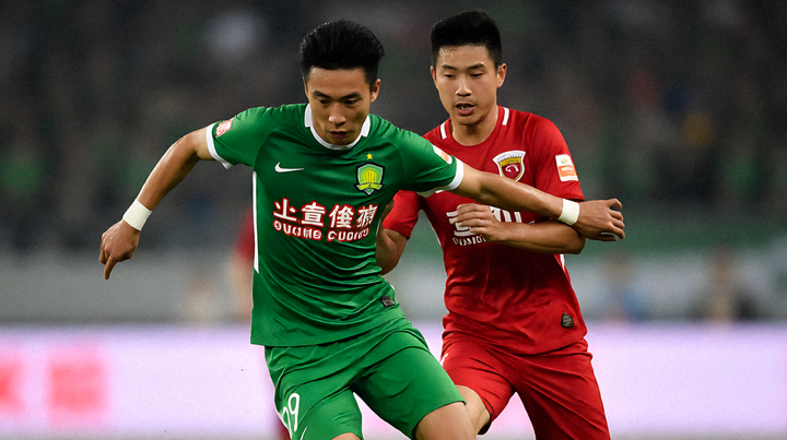 足球运动员在比赛中带球突破,防守球员贴身跟防的赛场特写